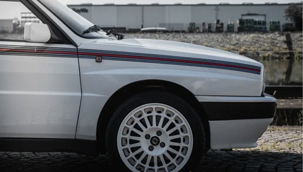 Angeschnittene Seitenansicht eines Lancia Delta HF Integrale EVO 16V. Feine dünne Streifen in Blau und Rot ziehen sich über die gesamte Seite des Autos.